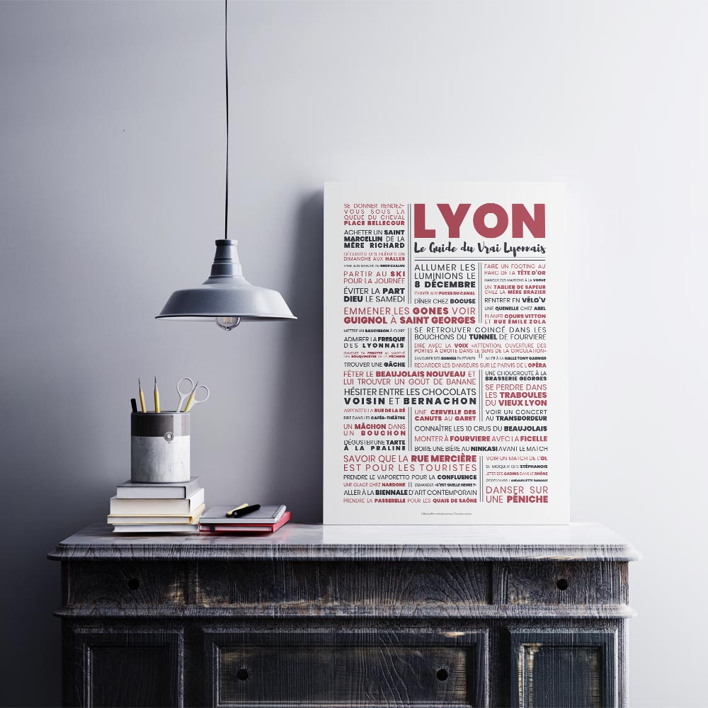 Affiche Lyon Le Guide du Vrai Lyonnais posée sur un meuble vintage avec pot à crayons et livres, ambiance atelier