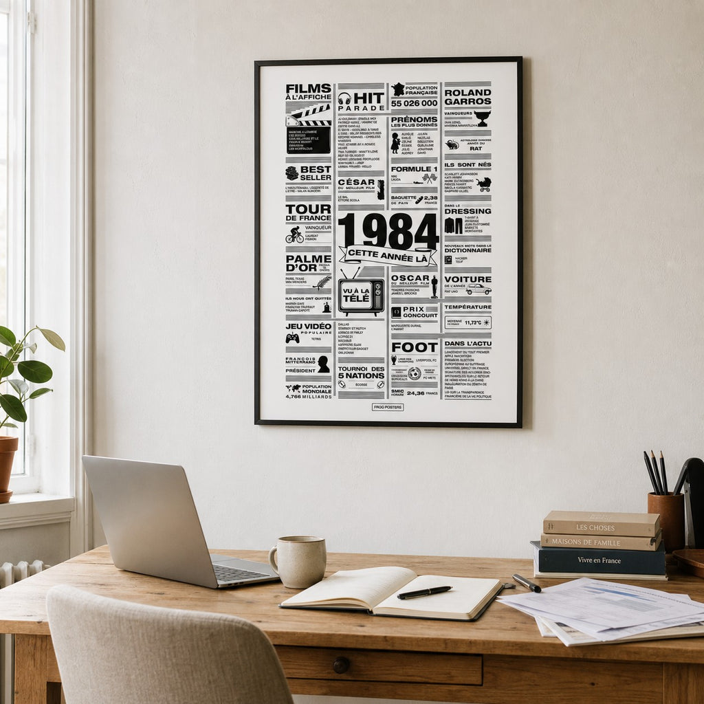 Affiche année 1984 encadrée dans un bureau français lumineux avec table en bois, laptop et livres, poster rétrospective année de naissance 1984, idée cadeau anniversaire, décoration murale rétro noir et blanc