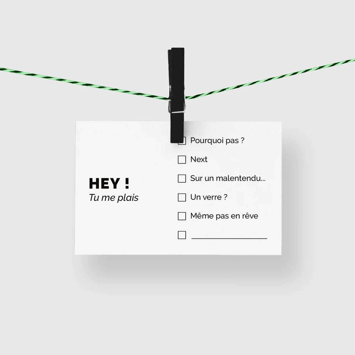 Carte de visite humour « Hey ! Tu me plais » suspendue à une corde à linge par une pince noire