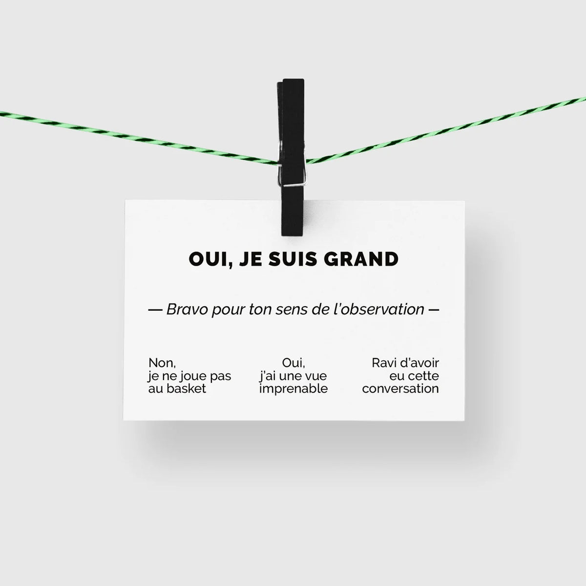 Carte de visite humour « Oui, je suis grand » suspendue à une corde à linge par une pince noire