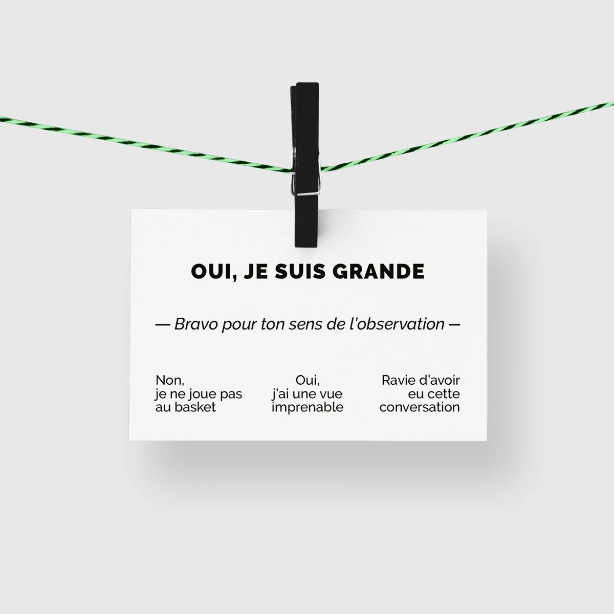 Carte de visite humour « Oui, je suis grande » suspendue à une corde à linge par une pince noire