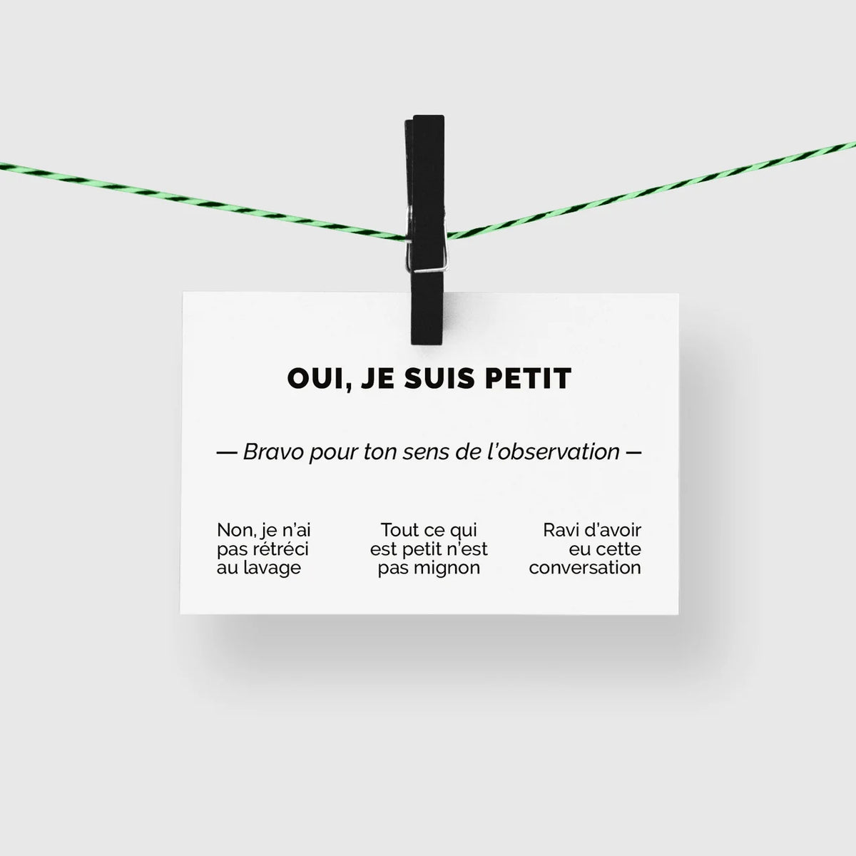 Carte de visite humour « Oui, je suis petit » suspendue à une corde à linge par une pince noire