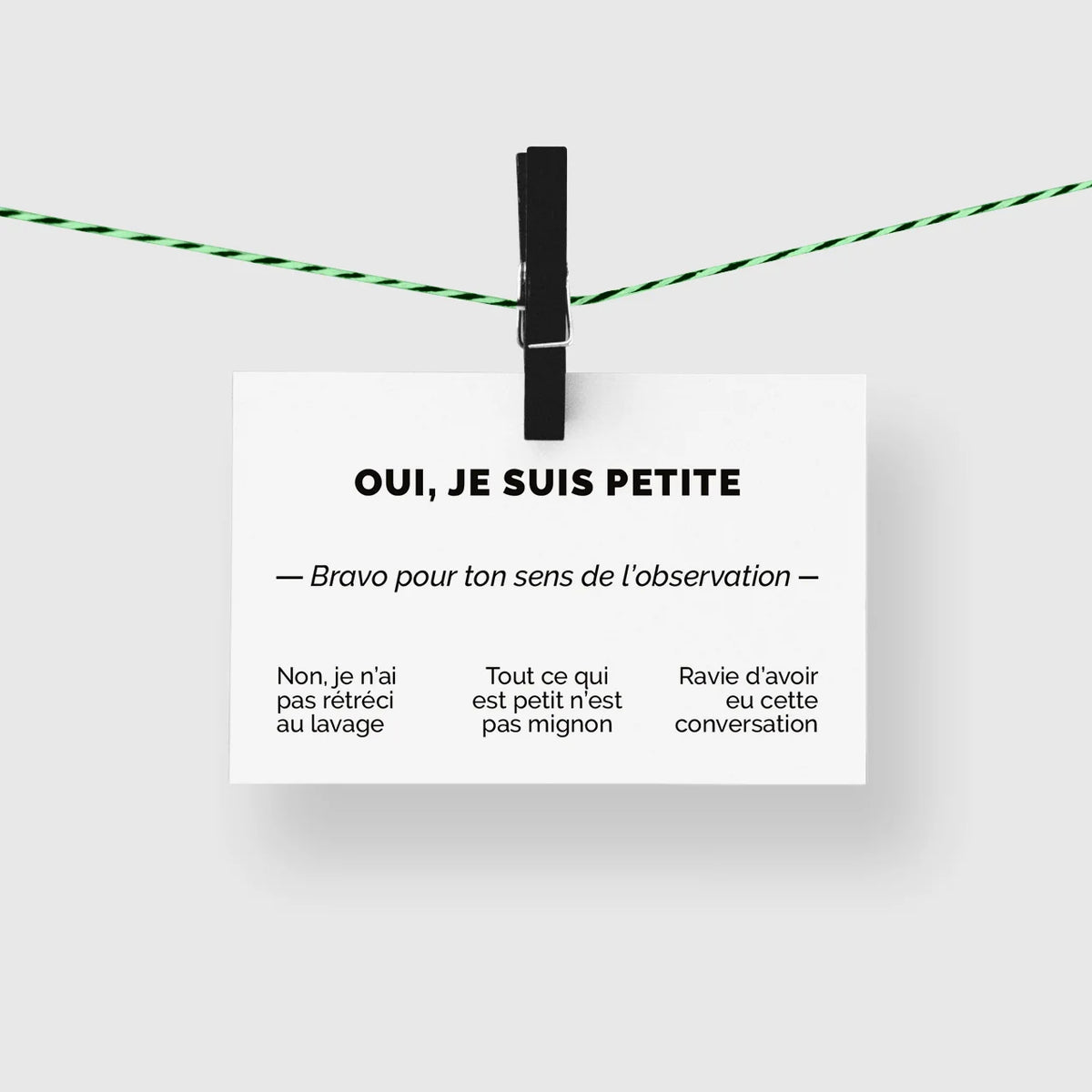 Carte de visite humour « Oui, je suis petite » suspendue à une corde à linge par une pince noire