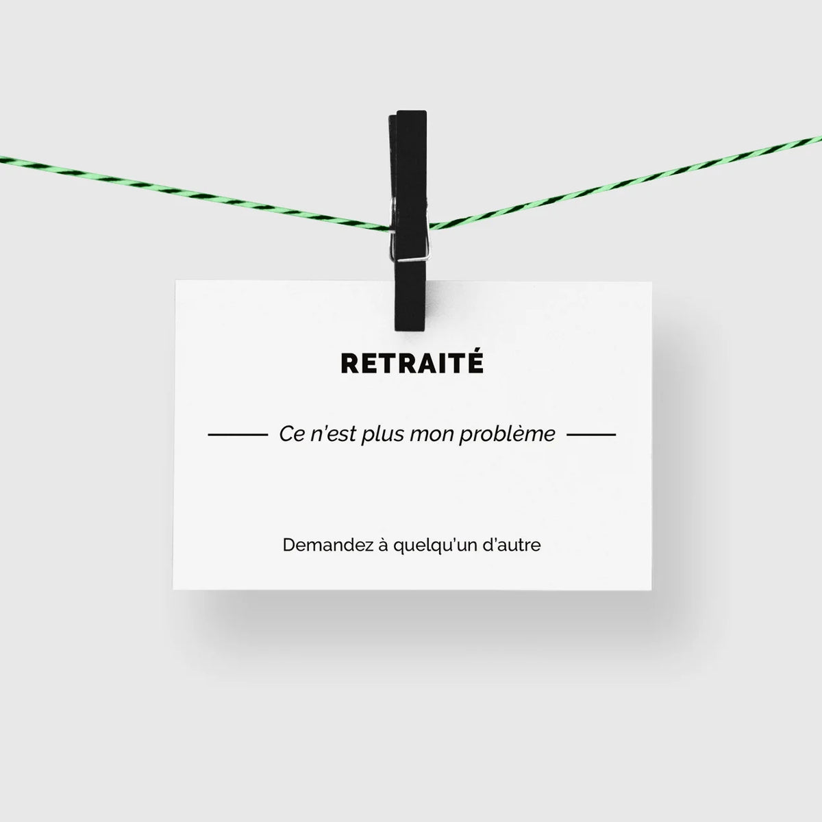 Carte de visite humour « Retraité » suspendue à une corde à linge par une pince noire