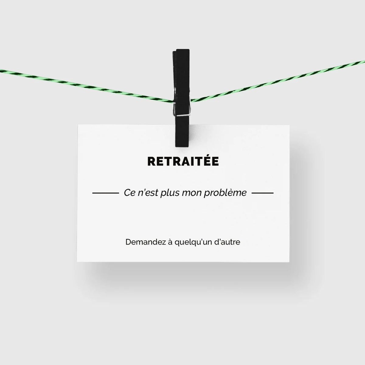 Carte de visite humour « Retraitée » suspendue à une corde à linge par une pince noire