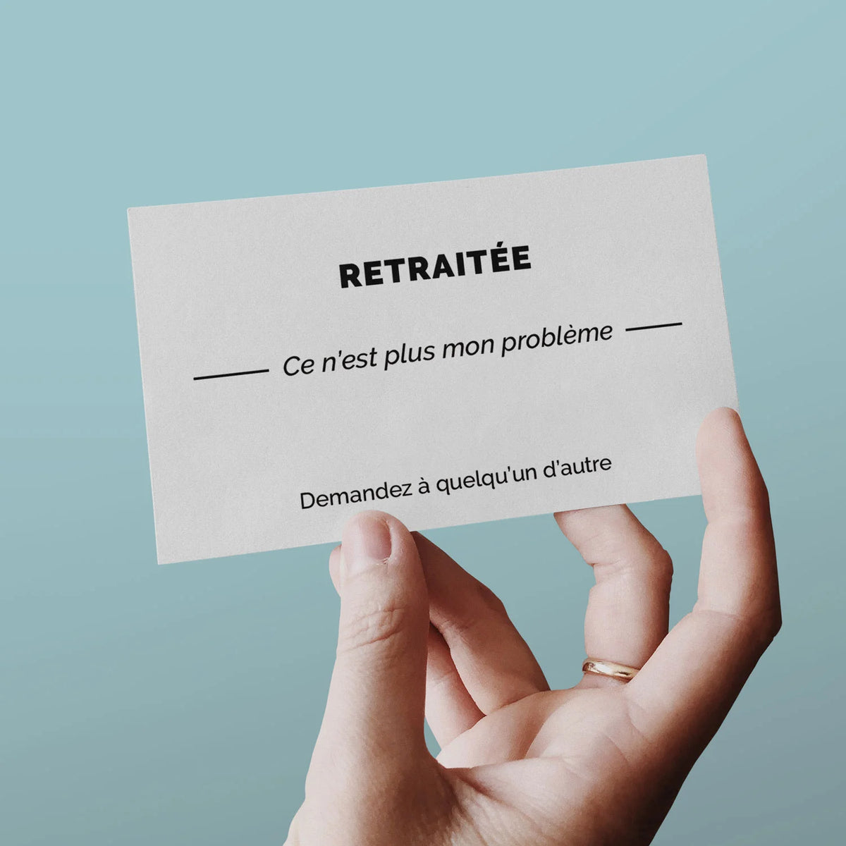 Main tenant une carte de visite « Retraitée » sur fond bleu