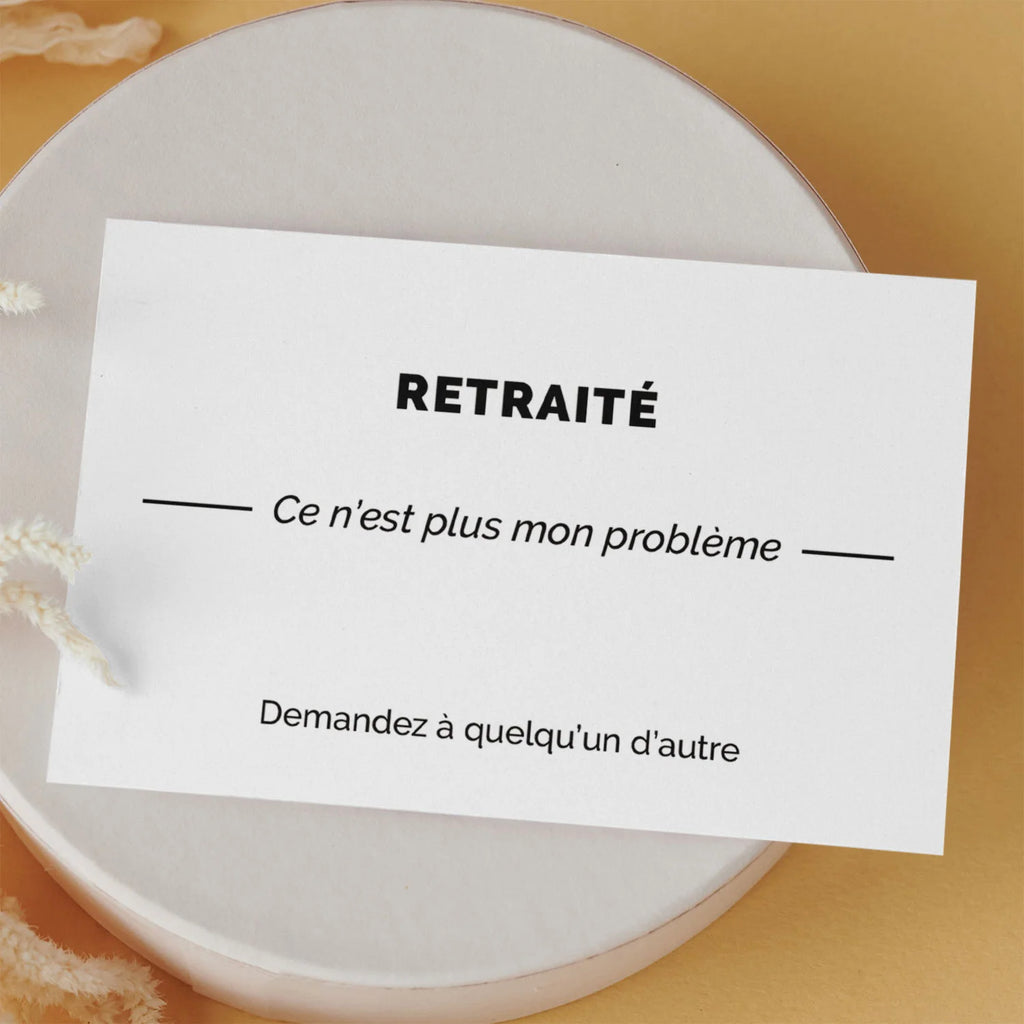 Carte de visite drôle « Retraité » posée sur une boîte ronde, fond orange