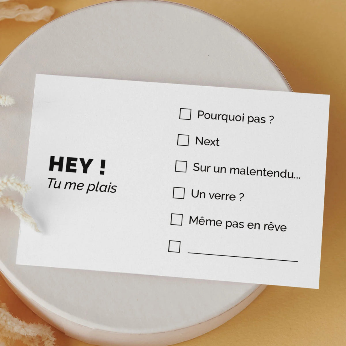 Carte de visite drôle « Hey ! Tu me plais » posée sur une boîte ronde, fond orange